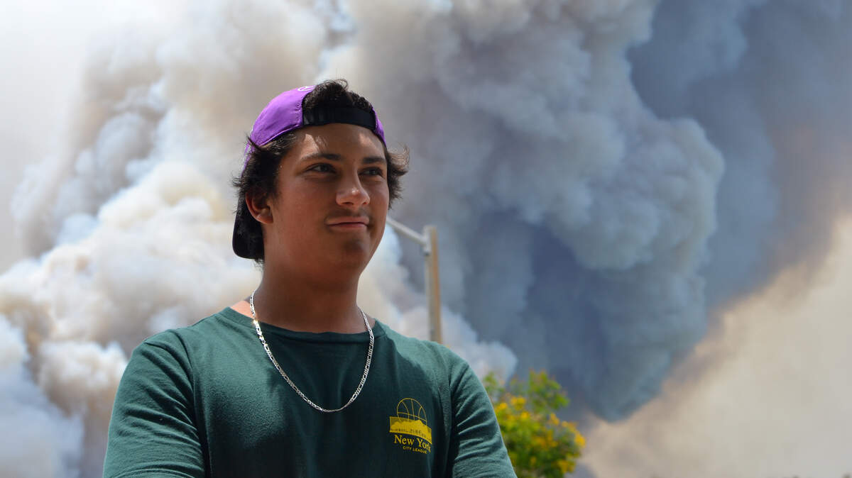 Adam Arenas, 14, stands outside his Northwest Doral home on June 18, 2026, as the Well and Quarry 2 fires burn just miles away from his house.